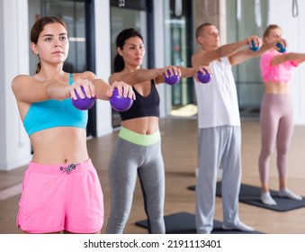 Portrait Of Young Woman Doing Workout With Toning Weight Balls At Group Pilates Class