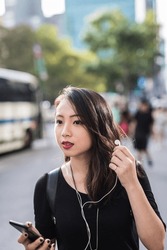 Portrait Of Young Woman With Earphones And Cell Phone Watching Something