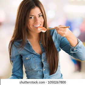 Portrait Of A Young Woman Eating Salmon Sushi against an abstract background