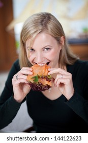 Portrait Of Young Woman Eating Salmon Roll In Restaurant