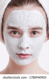 Portrait Of Young Woman With Face Pack And Towel Wrapped Around Head Against White Background