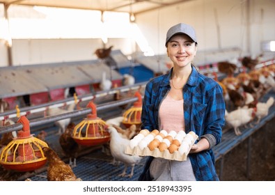 Portrait of young woman farmer holding fresh eggs in hands in henhouse - Powered by Shutterstock