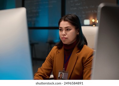 Portrait of young woman as female computer programmer looking at screen while working in cybersecurity department copy space