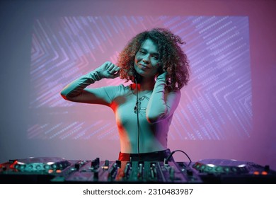 Portrait of young woman as female DJ looking at camera at nightclub, copy space - Shutterstock ID 2310483987