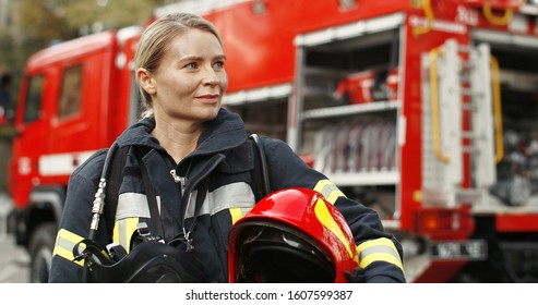 Портрет молодой женщины-пожарного, стоящего возле пожарной машины. 