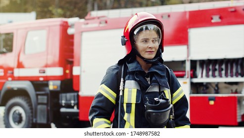 Portrait of young woman firefighter standing near fire truck. 