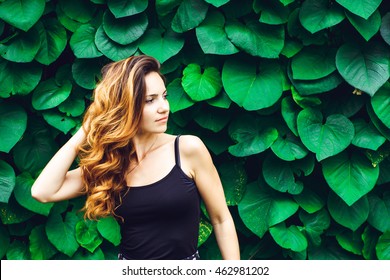 Portrait Of Young Woman With The Freckles And Curly Hair, Against Background Of Summer Green Park, Green Leaves. Natural Beauty.