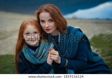 Portrait of a young woman and a girl with long red hair in nature. Boho style