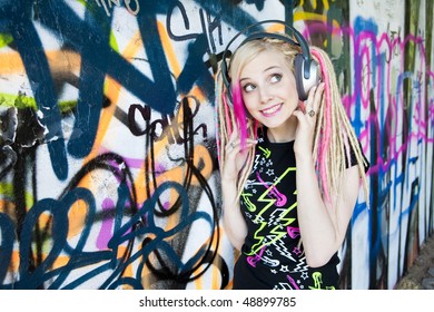 Portrait Of Young Woman With Headphones At Graffitti Wall