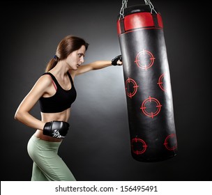 Portrait of young woman hitting the punching bag - Powered by Shutterstock