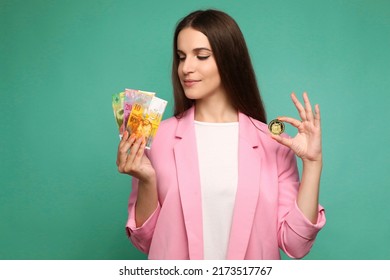 Portrait of young woman holding crypto currency and swedish krona banknotes and looking on swedish krona