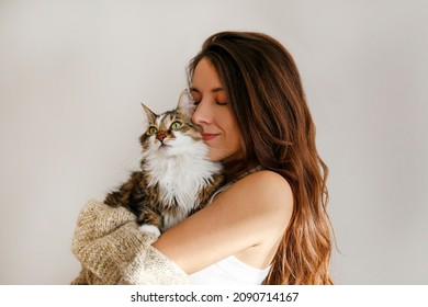 Portrait of young woman holding cute siberian cat with green eyes. Female hugging her cute long hair kitty. Background, copy space, close up. Adorable domestic pet concept. - Shutterstock ID 2090714167