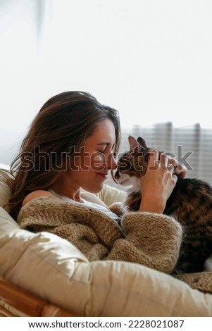 Portrait of young woman holding cute norwegian cat with green eyes. Female hugging her cute long hair kitty. Background, copy space, close up.