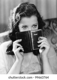 Portrait of a young woman holding a diary and thinking