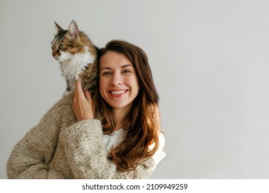 Portrait of young woman holding her siberian cat with green eyes. Female and cute long hair kitty sitting on her shoulder. Background, copy space, close up. Adorable domestic pet concept. - Powered by Shutterstock