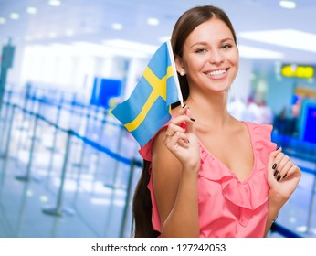 Portrait Of A Young Woman Holding Swedish Flag at an airport