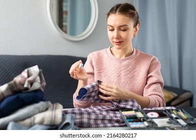 Portrait of young woman housewife stitching button on shirt - Shutterstock ID 2164280217