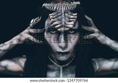 Portrait of young woman in image of humanoid and extraterrestrial alien with horns on her head and demonic eyes.