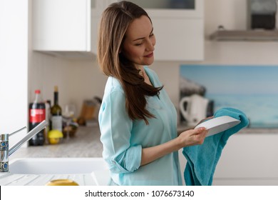 Portrait Of A Young Woman In The Kitchen Interior Wipe With A Dry Towel Clean Dishes, Cleaning The House.