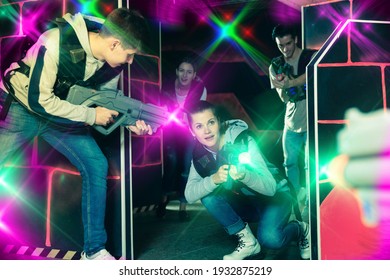 Portrait of young woman with laser gun having fun on dark lasertag arena