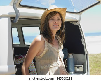 Portrait of young woman leaning on open tailgate of van at beach - Powered by Shutterstock