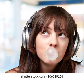 portrait of a young woman listening to music with bubble gum over an abstract background