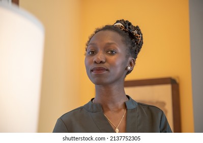 Portrait Of Young Woman Low Angle Portrait Looking At Camera Focused With Green Shirt, Yellow Walls Background	