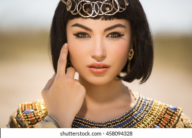 Portrait of young woman with luxury makeup. Beautiful girl with stylish haircut agaist desert background, young lady wearing fashionable golden necklace and dress. Beauty salon consept