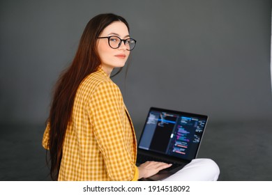 Portrait of young woman mobile developer with laptop, writes program code on a computer, programmer work.