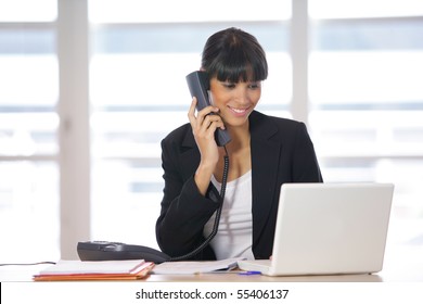 Portrait of a young woman on phone in front of a laptop computer - Shutterstock ID 55406137