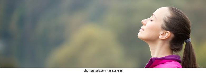 Portrait of a young woman outdoors in a sportswear, head up, her eyes closed. Concept photo, copy space. Horizontal photo banner for website header design with copy space for text
