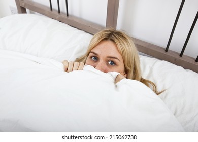 Portrait Of Young Woman Peeking Over Quilt