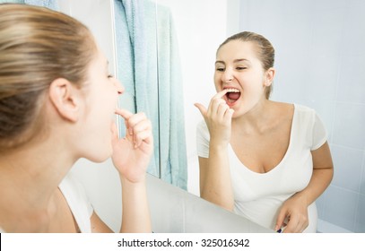 Portrait Of Young Woman Picking Food Stuck In Teeth With Finger