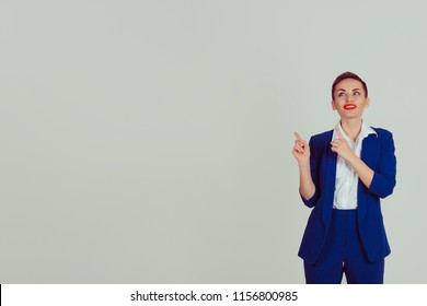 Portrait Young Woman Pointing With Index Fingers Up To The Copy Space Isolated On Gray Wall Background. Positive Face Expression Body Language Life Perception 