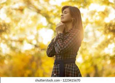 portrait of a young woman praying in nature, the girl thanks God with her hands folded at her chin, a conversation with the Creator, the concept of religion