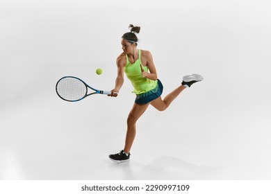 Portrait of young woman, professional female tennis player hitting ball with racket, training against white studio background. Concept of professional sport, movement, health, action. Ad - Powered by Shutterstock