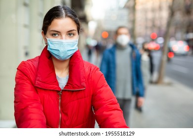 Portrait Of Young Woman In Protective Mask Strolling On The Electric Scooter Along Spring City Street