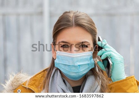 Portrait young woman with protective mask and gloves holding smartphone - coronavirus pandemic alert