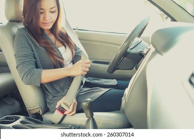 Portrait Of Young Woman Putting On A Seatbelt For Safety