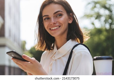 Portrait Of Young Woman Recording Voice Messages On Smartphone, Smiling Girl Texting Messages On Smartphone While Walking Near Office Building