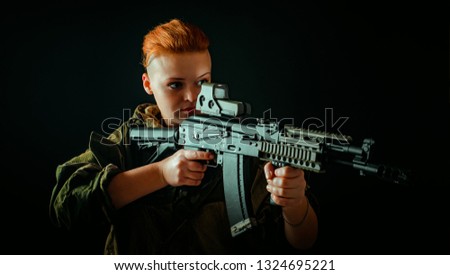 Portrait of young woman with red hair, young girl takes aim at the sight in military uniform