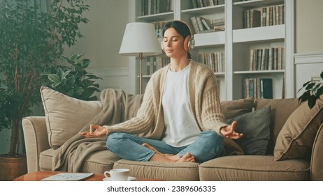 Portrait of young woman relaxing at home and listening music. Girl sitting on sofa. Relaxation, Meditation and Mindfulness - Powered by Shutterstock