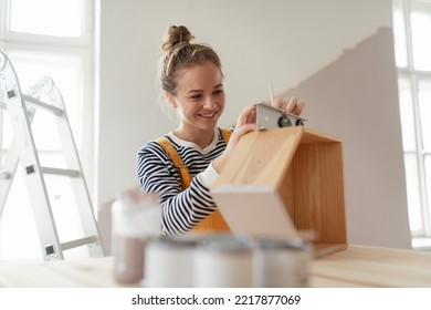 Portrait of young woman remaking shelf in her new flat. Concept of reusing materials and sustainable lifestyle. - Powered by Shutterstock