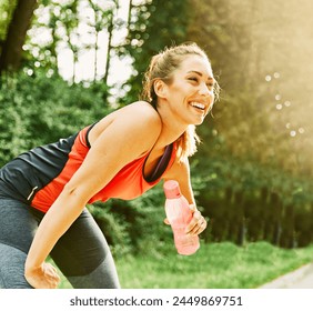 Portrait of a young woman running and exercising, exhausted tired resting and holding bottle  with enrgy drink or water after running jogging exercisingin a park outdoors - Powered by Shutterstock