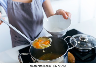 Portrait Of Young Woman Serving Vegetable Soup In The Kitchen.