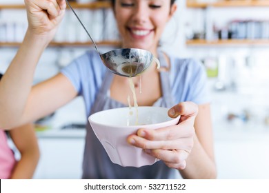 Portrait Of Young Woman Serving Vegetable Soup In The Kitchen.