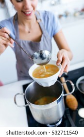 Portrait Of Young Woman Serving Vegetable Soup In The Kitchen.