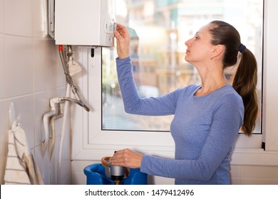 Portrait Of Young Woman Setting Up Gas Boiler At Home