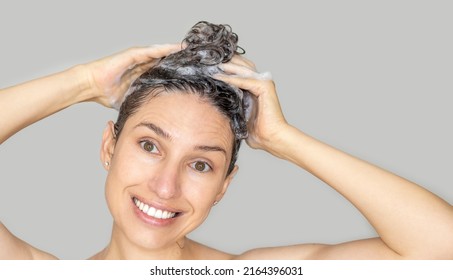 Portrait Of Young Woman Shampooing Hair.smiling Girl Isolated On Grey Background.hair Care Concept.mock Up Free Space For Text,advertising Banner.no Makeup Woman,beautiful Smile,natural Teeth