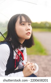 Portrait Of Young Woman Short Hair Wear Japanese Student High School Uniform With Umbrella Under Rain Drop. People Cosplay In Japan Culture Lifestyles.